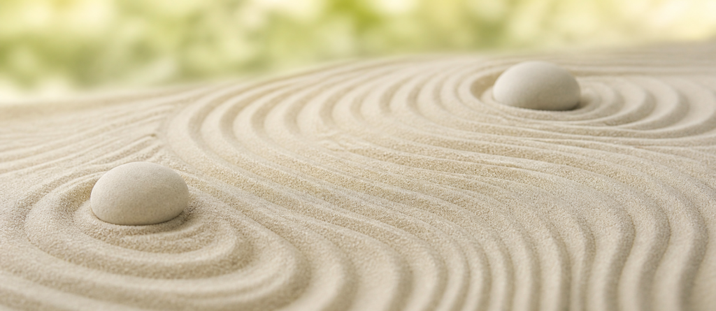 Soft raked sand patterns with two pale stones in a serene Zen garden