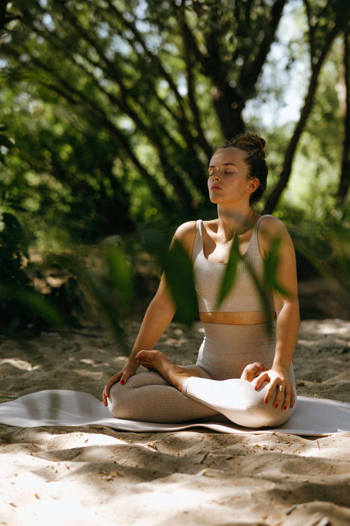 Woman meditating outdoors on a yoga mat